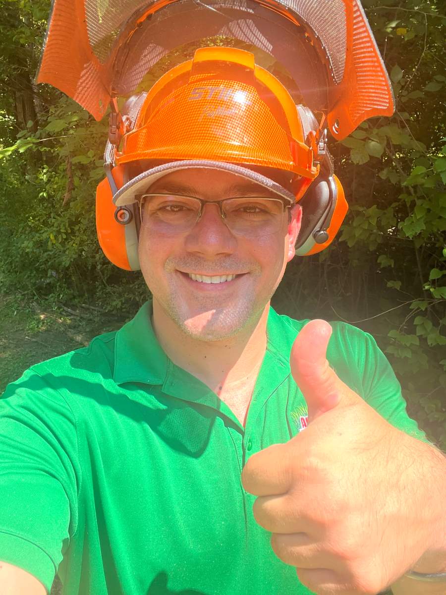 Anthony wearing a protective helmet after tree removal with thumbs up